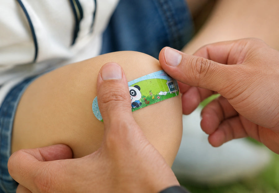 A child-friendly patterned plaster from the Moor School Kit being applied to a child's knee