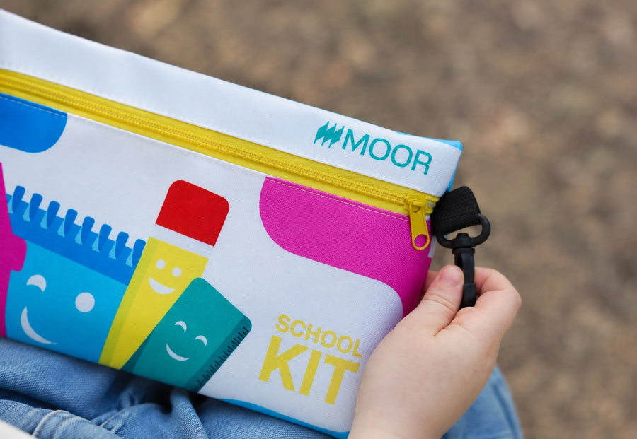 Close-up of a child holding the Moor School Kit pouch by its clip